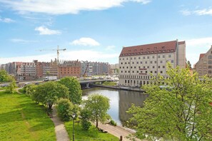 A riverside view with a bridge, a hotel with a red roof, and a construction crane in the background. - Rezydencja Wintera 1B | River View (Gdańsk)