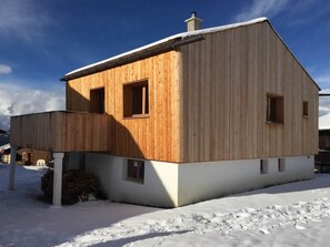 A wooden cabin with a sloped roof, a chimney, and a small porch area. - Chalet Bergfink 4-Bettwohnung, Dusche, WC 4-Bettwohnung by Interhome (Rosswald)