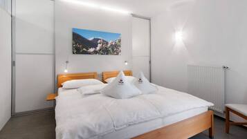 Ein Schlafzimmer mit einem Bett, Kissen, einem Holzkopfende, einem an der Wand hängenden Bild, einem Nachttisch und einem Heizkörper.