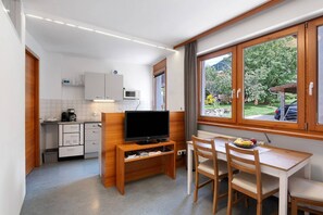 Eine kleine Küche mit Fernseher, Essbereich und einem Fenster mit Blick auf Grünflächen.