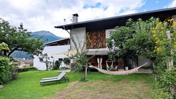 A modern house with a hammock, a lounge chair, and a view of mountains.