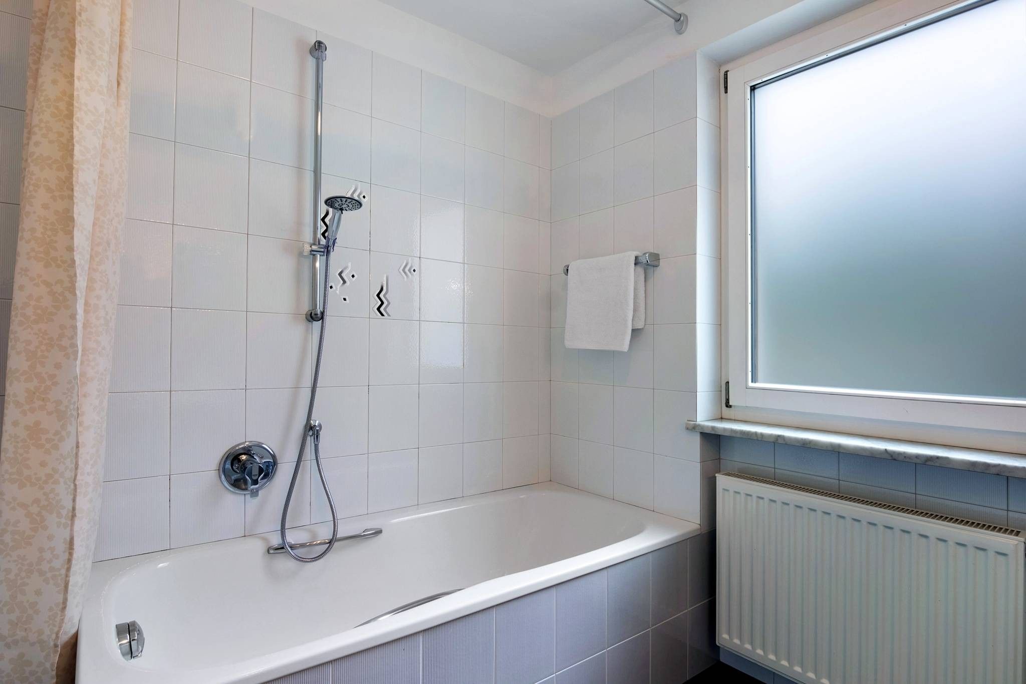 Ein Badezimmer mit einer Badewanne, einer Dusche und einem Fenster.