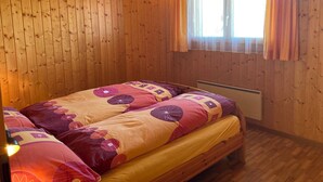Et hyggeligt værelse i en træhytte med en seng, et vindue med gardiner og en radiator.