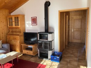 Uma sala de estar acolhedora com televisão, armários de madeira, lareira e um tapete vermelho.