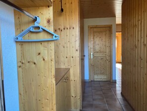 A wooden hallway with a door at the end, a coat hanger on the wall, and a small shelf.