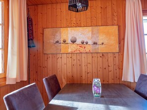 A wooden-paneled room with a table and chairs, a wall-mounted artwork, and a bell.