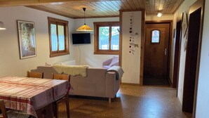 Ein gemütliches Interieur mit Esstisch, Sofa und an der Wand montiertem Fernseher.