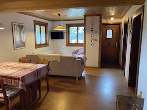 Ein gemütliches Interieur mit Esstisch, Sofa und an der Wand montiertem Fernseher.
