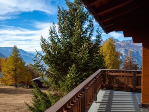 Ein Holzbalkon mit Blick auf einen Wald und Berge.