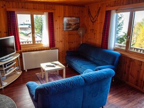 Ein Holzinterieur mit einem blauen Sofa, einem Fernseher und einem Bild an der Wand.
