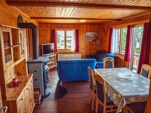 Un interior de cabaña acogedor con un sofá, una mesa de comedor y una televisión.