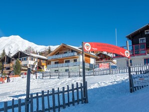 Ein Skigebiet mit Holzzaun, rotem Schild und Gebäuden mit schneebedeckten Dächern.