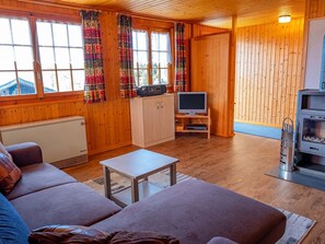 Ein gemütliches Blockhaushaus-Interieur mit einer Couch, einem Fernseher und einem Kamin.