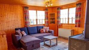 A cozy cabin interior with a sofa, ottoman, and a small table. - Chalet Valeria 4-Bettwohnung, Parterre, 2 Schlafräume Valeria EG by Interhome (Rosswald)