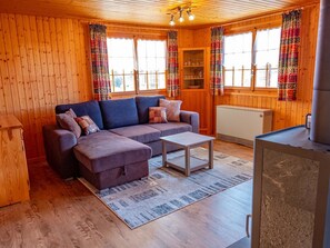 Ein gemütliches Blockhaus-Interieur mit Sofa, Hocker und einem kleinen Tisch.