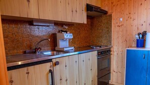 A kitchen with wooden cabinets, a stainless steel sink, a coffee machine, and a stove. - Chalet Valeria 4-Bettwohnung, Parterre, 2 Schlafräume Valeria EG by Interhome (Rosswald)