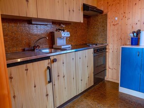 Eine Küche mit Holzausstattung, einem Edelstahlspülbecken, einer Kaffeemaschine und einem Herd.