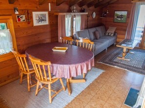 A cozy cabin interior with a dining table, wooden chairs, a sofa, and a rug. - Chalet Alphütte Appartement/Fewo, Dusche, WC 4-Bettwohnung Dachgeschoss by Interhome (Rosswald)
