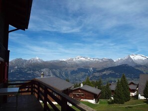 Vista de la montaña con una cabaña de madera y un balcón.