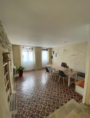 A dining area with a table and chairs, a potted plant, and patterned flooring. - Maison de capitaine, idéale pour les grandes familles, au coeur de St Gildas (Saint-Gildas-de-Rhuys)