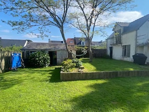 A residential backyard with a well-maintained lawn, a hammock, and a blue laundry cart. - Maison de capitaine, idéale pour les grandes familles, au coeur de St Gildas (Saint-Gildas-de-Rhuys)