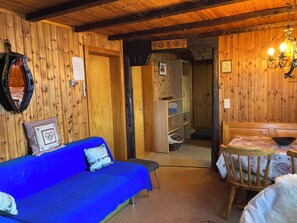 Ein Holzinterieur mit einem blauen Sofa, einem Esstisch mit Stühlen und einem Spiegel an der Wand.
