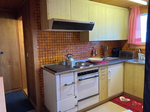 A compact kitchen with a tiled backsplash, a kettle, a toaster, and a sink. - Chalet Lueg uf Belalp Appartement/Fewo, Parterre Appartement/Fewo, Parterre by Interhome (Rosswald)