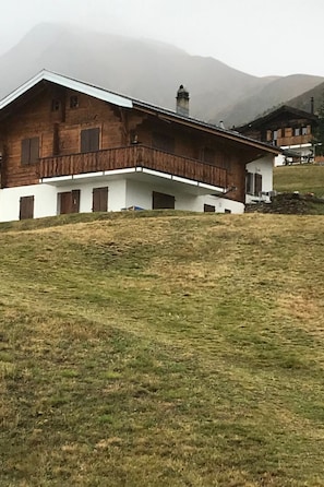 A two-story wooden house with a balcony, set against a backdrop of mountains. - Chalet Lueg uf Belalp Appartement/Fewo, Parterre Appartement/Fewo, Parterre by Interhome (Rosswald)