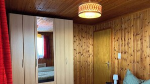 Un dormitorio con cama, armario, mesita de noche y lámpara.