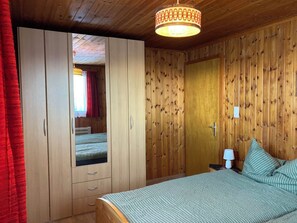 Ein Schlafzimmer mit Bett, Kleiderschrank, Nachttisch und Lampe.
