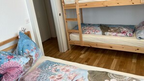 Ein Etagenbett mit floralem Bettzeug, Holzboden und eine Tür zu einem anderen Zimmer.