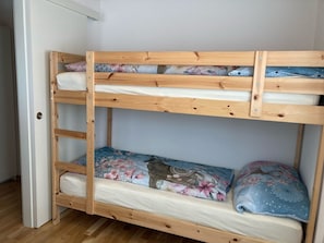 Un lit superposé à deux niveaux, chaque niveau étant équipé d’un matelas et d’un oreiller.