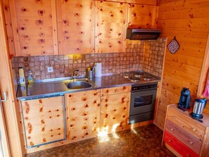A compact kitchen with wooden cabinets, a stainless steel sink, a stove, and a small coffee maker. - Chalet Valeria 5-Bettwohnung, 1. Stock, 2 Schlafräume Valeria OG by Interhome (Rosswald)