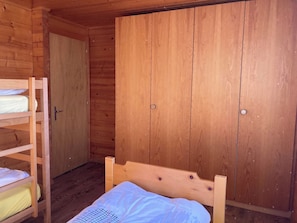 A wooden room with bunk beds and a wardrobe. - Chalet Valeria 5-Bettwohnung, 1. Stock, 2 Schlafräume Valeria OG by Interhome (Rosswald)