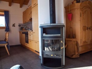 Een knus keuken met houten kastjes, een inbouwfornuis en een eethoek met een stoel.