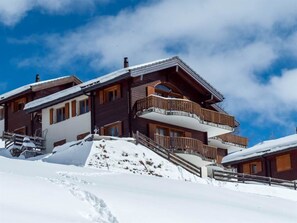 A multi-story wooden chalet with balconies and a ski slope in the foreground. - Chalet Bergkristall 4-Bettwohnung, Dusche, WC 4-Bettwohnung, Dusche, WC by Interhome (Rosswald)