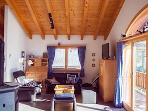 A cozy living room with a wooden ceiling, a sofa, a coffee table, and a television. - Chalet Bergkristall 4-Bettwohnung, Dusche, WC 4-Bettwohnung, Dusche, WC by Interhome (Rosswald)