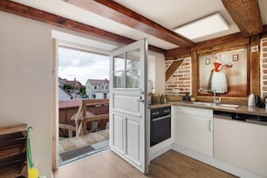 A kitchen with a modern design, featuring a built-in oven and dishwasher, a wooden ceiling, and a view of the street outside.