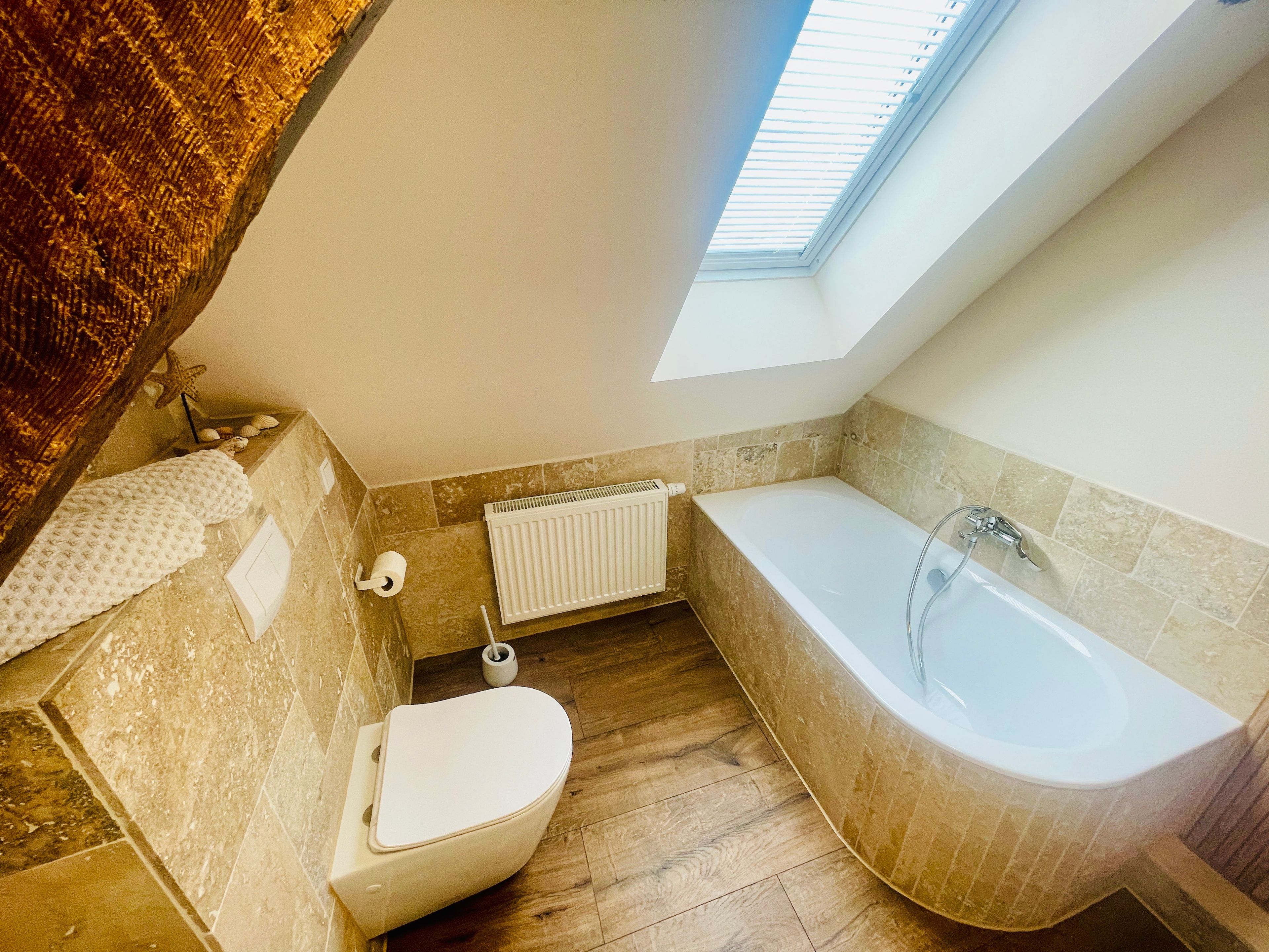 Une salle de bain avec une baignoire, des toilettes et une lucarne.