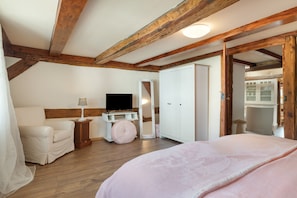 A bedroom with a bed, a television, a wardrobe, and a chair.