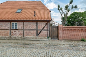 A traditional brick building with a tiled roof, a wooden door, and a small window.