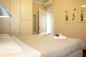 A hotel room with a bed, a wardrobe, a bathroom door, and wall art. - Apartment in Lucca with private furnished terrace (Lucca)