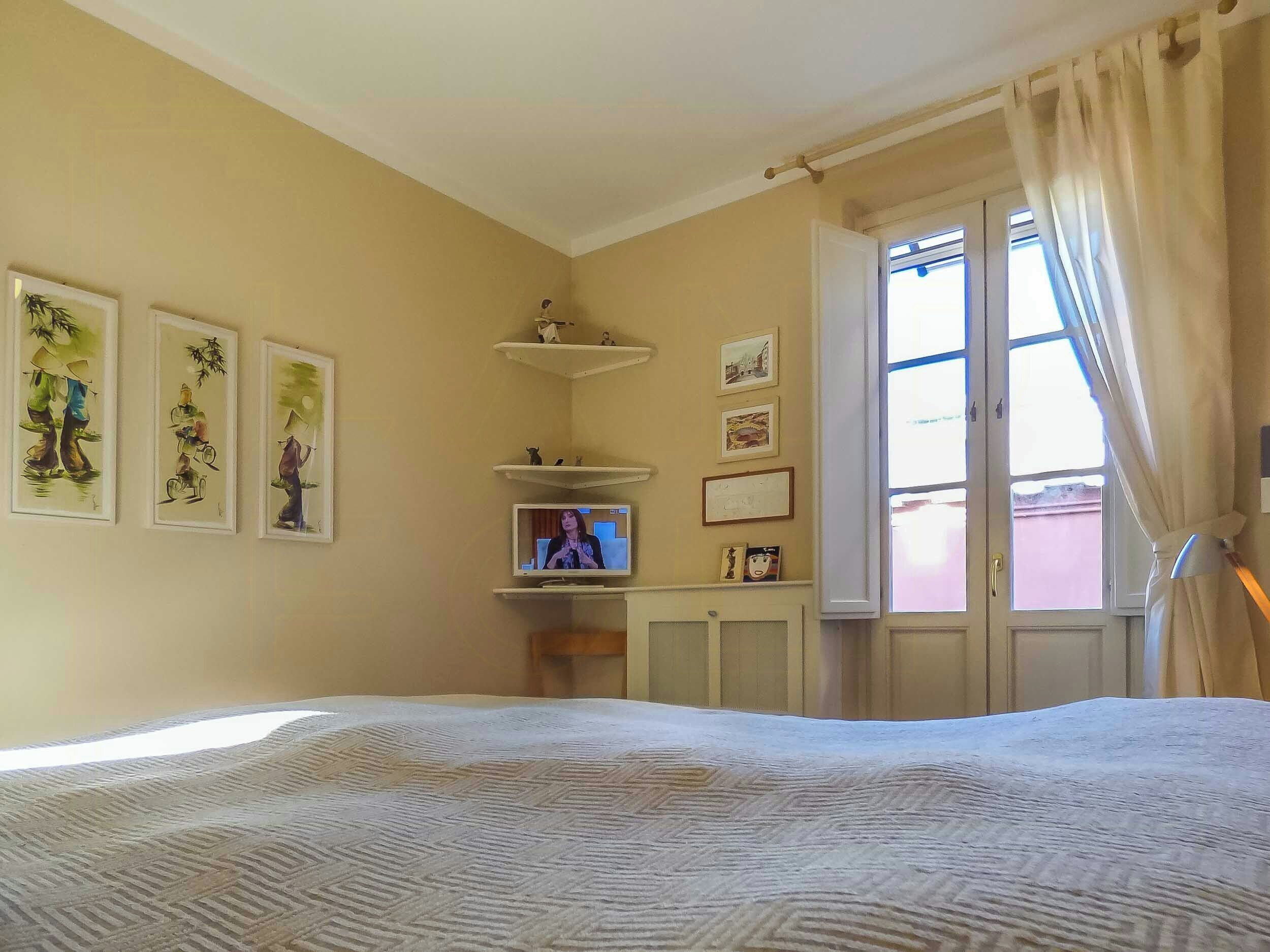 Un dormitori amb un llit, televisió i obra d'art a la paret.