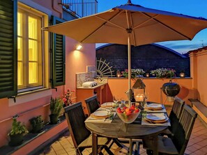 An outdoor dining area with a table set for four, surrounded by chairs, under a large umbrella. - Apartment in Lucca with private furnished terrace (Lucca)