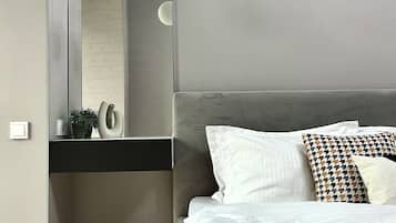 Une chambre à coucher moderne, comprenant un lit, une table de chevet, un miroir et un luminaire fixé au mur.
