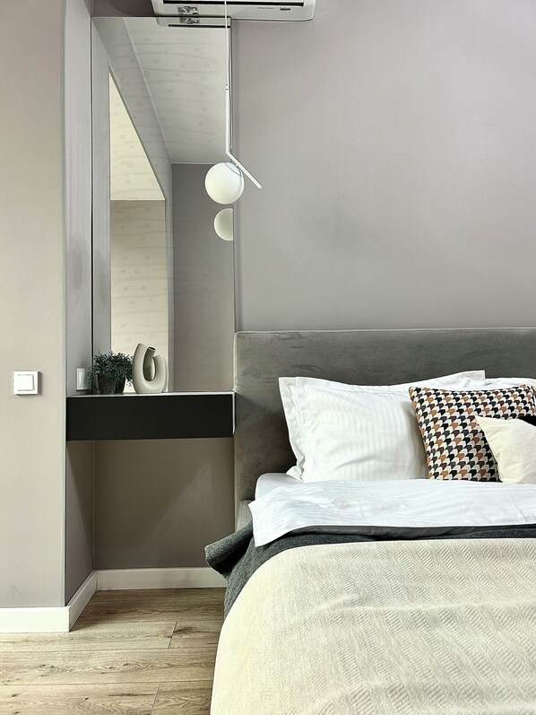 A modern bedroom with a bed, bedside table, mirror, and a wall-mounted light fixture. - Comfort city Residence near to MEGA (Almaty)