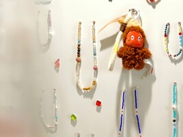 A variety of beaded necklaces and a plush toy with a tag.