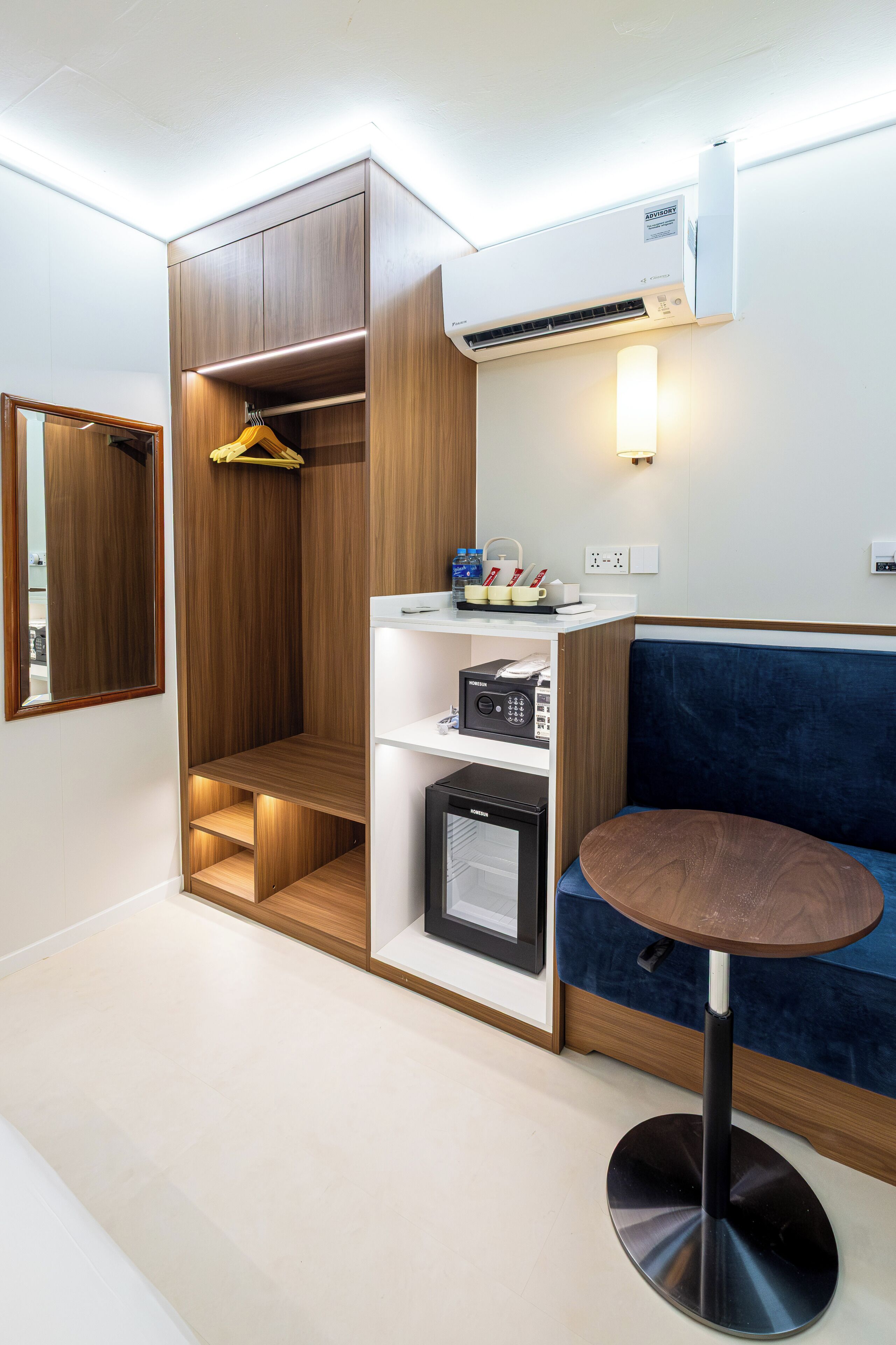 Habitación compacta con armario empotrado, una pequeña kitchenette, un área de descanso con una mesa redonda y un equipo de aire acondicionado de pared.