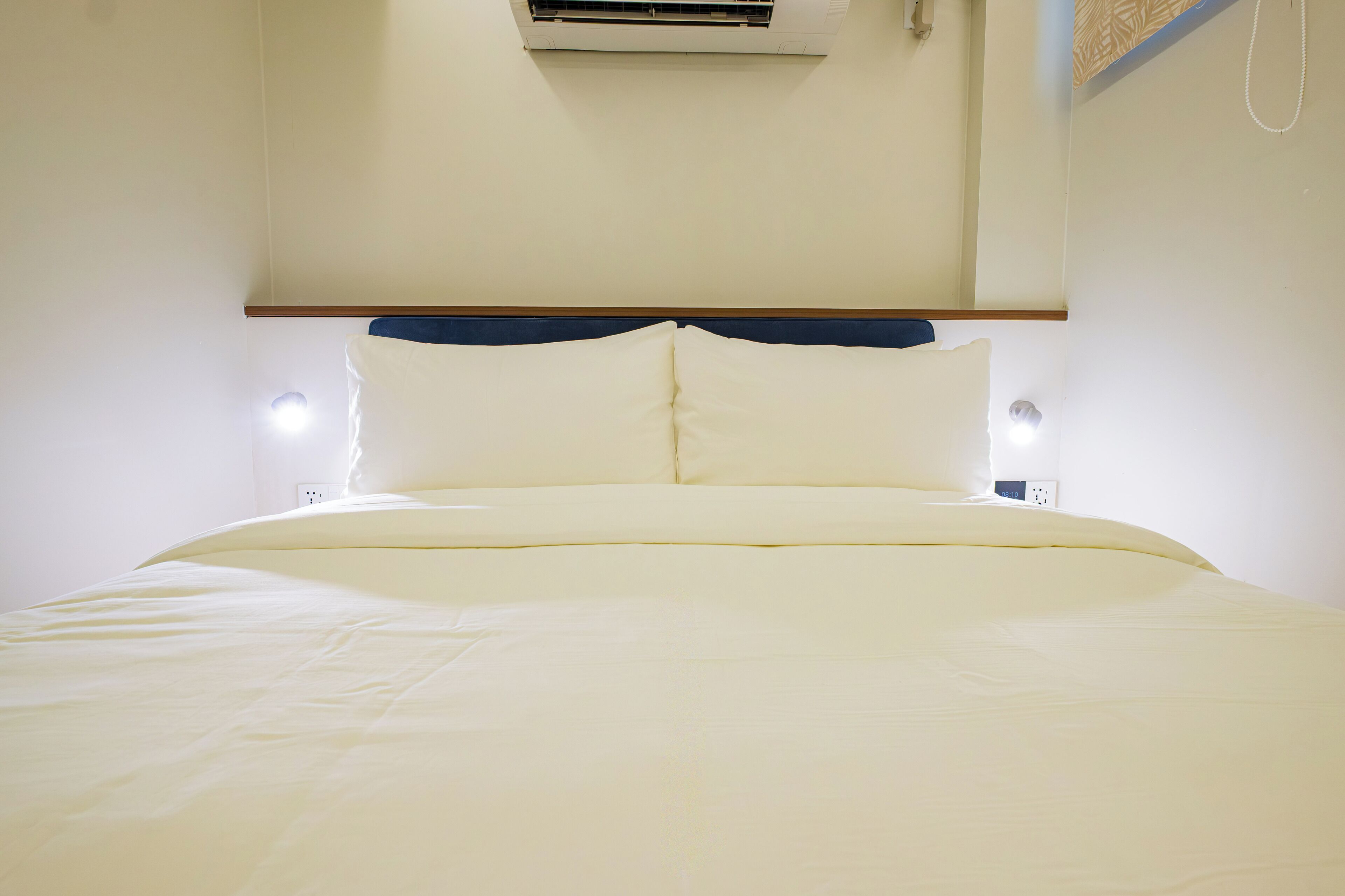 A bed with a wooden headboard, white bedding, and two bedside lamps.