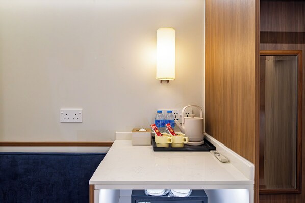 A hotel room with a white countertop, a wall-mounted light, a kettle, a coffee maker, and a tissue box. - Rest Rochor Hotel (Singapore)